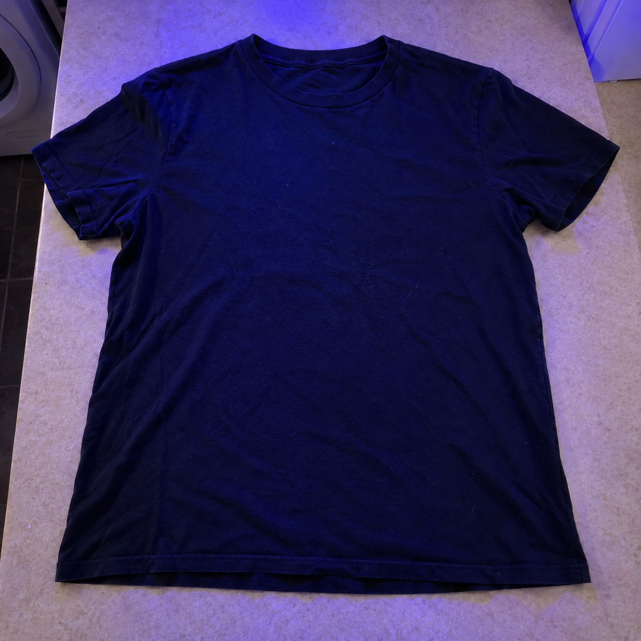 After view of the same navy T-shirt under blue lighting
