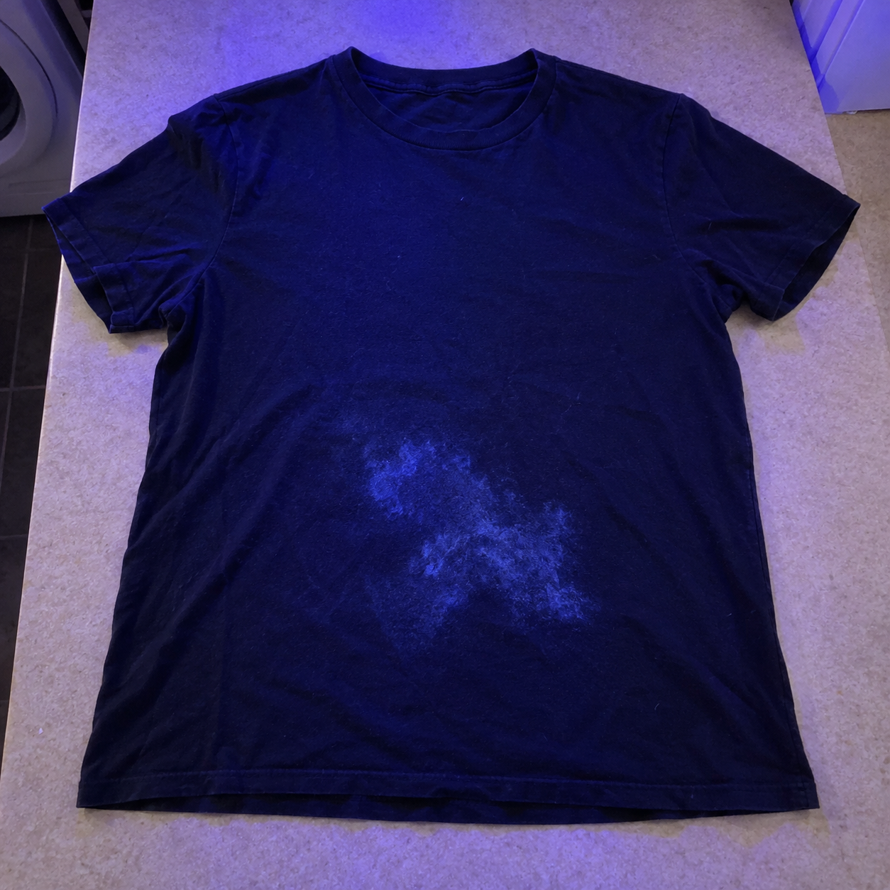 Before view of a navy T-shirt under blue lighting